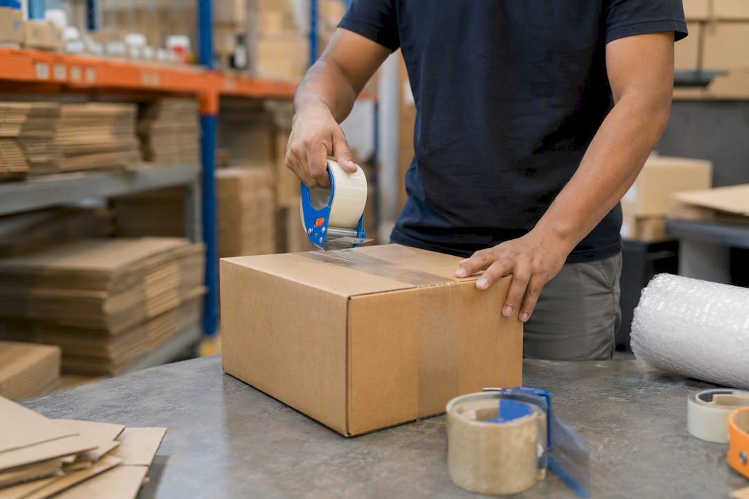 Hands sealing a shipment box with packing tape